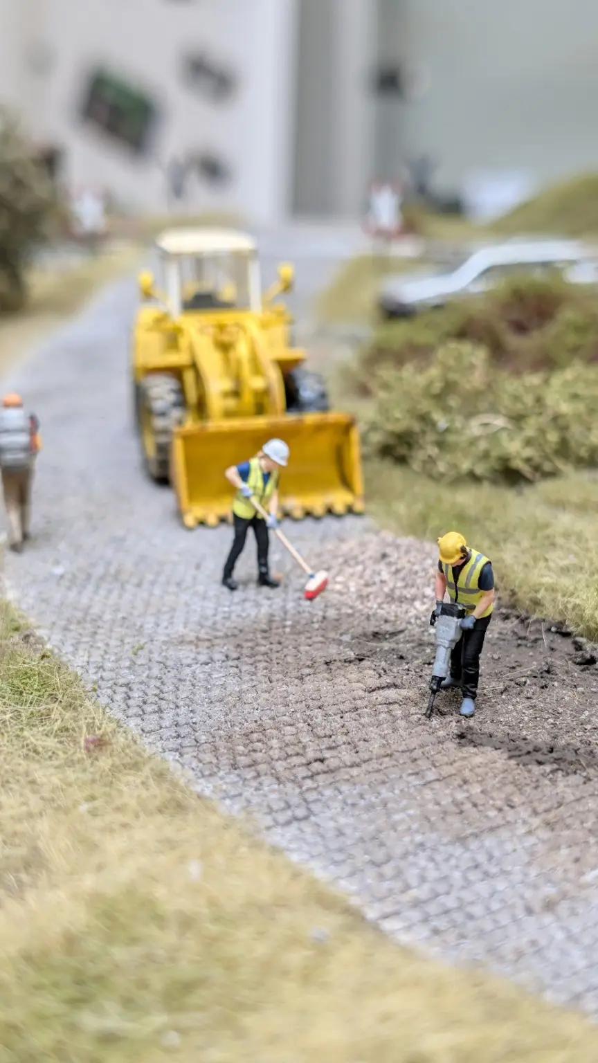 10 Arbeitsablauf verdichten &ndash; Presslufthammer, Besen und Radlader bilden eine klare Arbeitsfolge und machen die Szene unmittelbar verst&auml;ndlich.