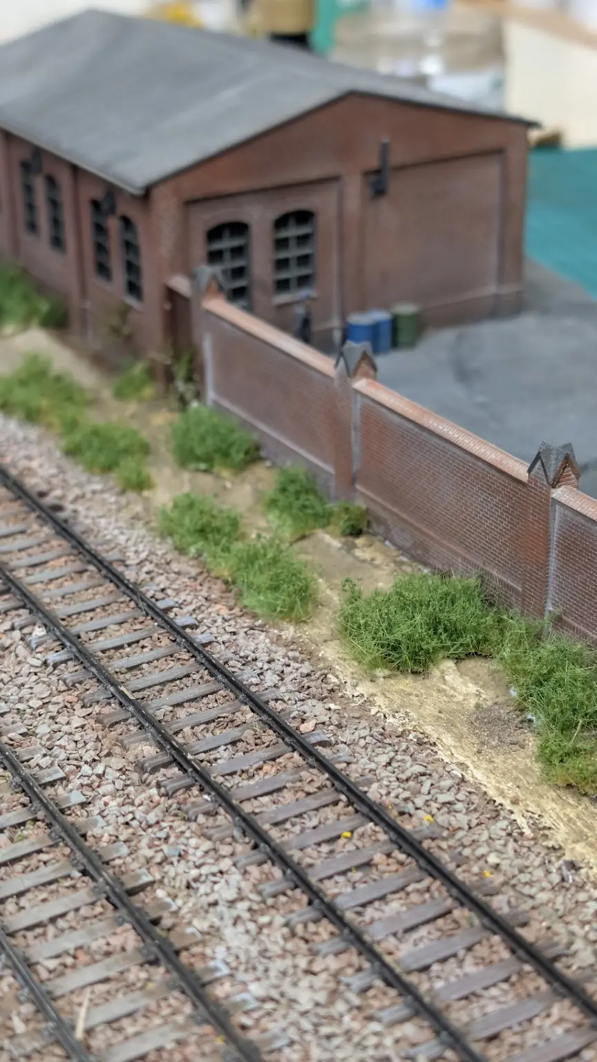 Fertiger &Uuml;bergang von Schotter und Boden zu Vegetation vor einem Backsteingeb&auml;ude