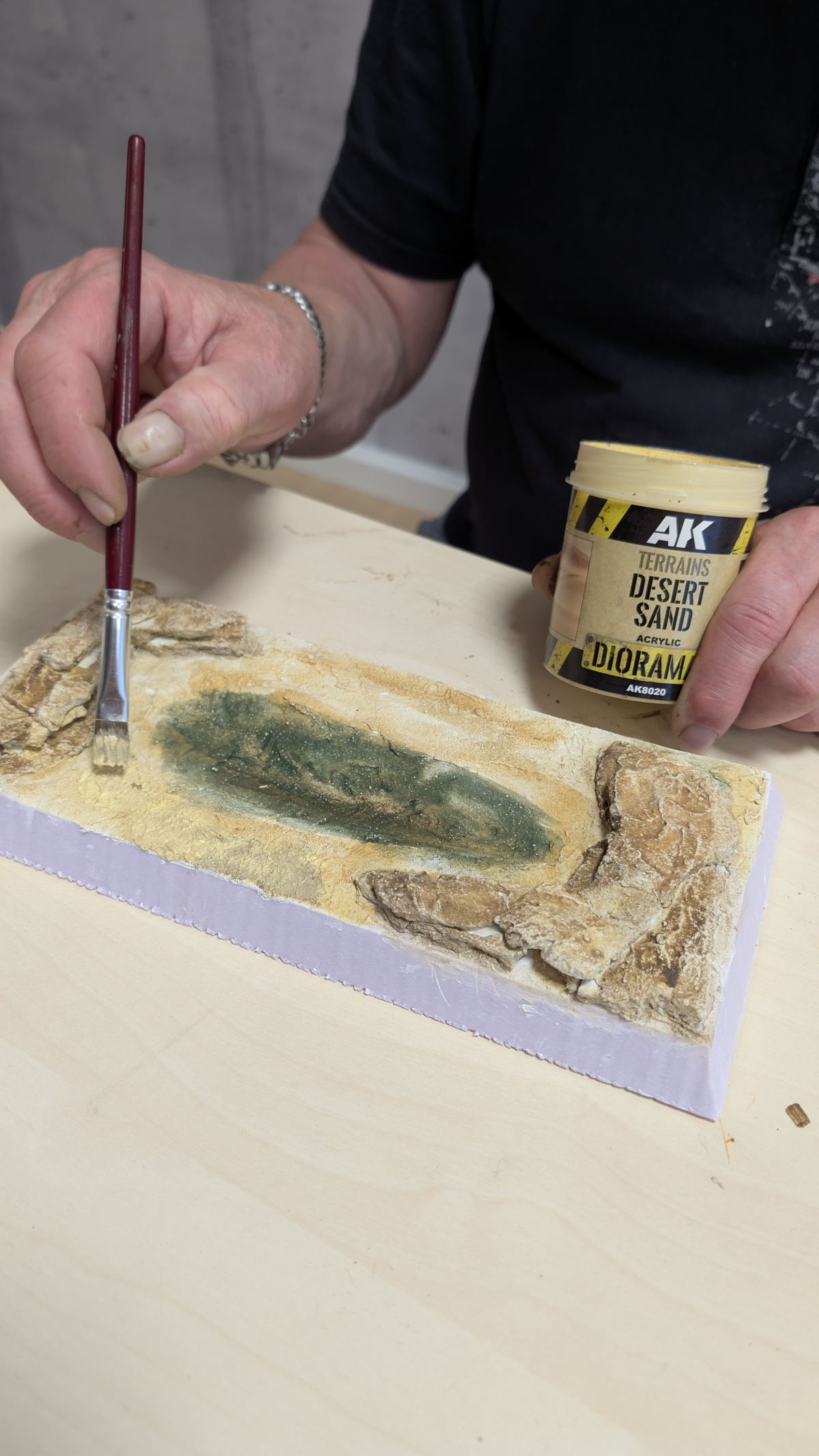 Flacher Pinsel setzt trocken abgestreifte Farbe auf die Gel&auml;ndefl&auml;che