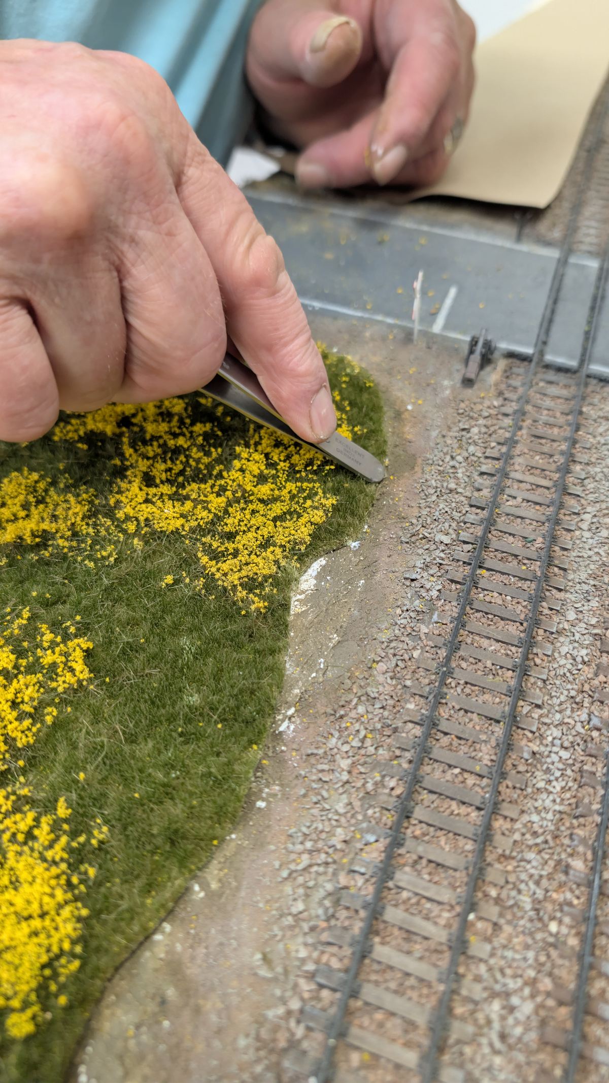 Finger dr&uuml;ckt den Rand der Grasmatte in die Schotterb&ouml;schung