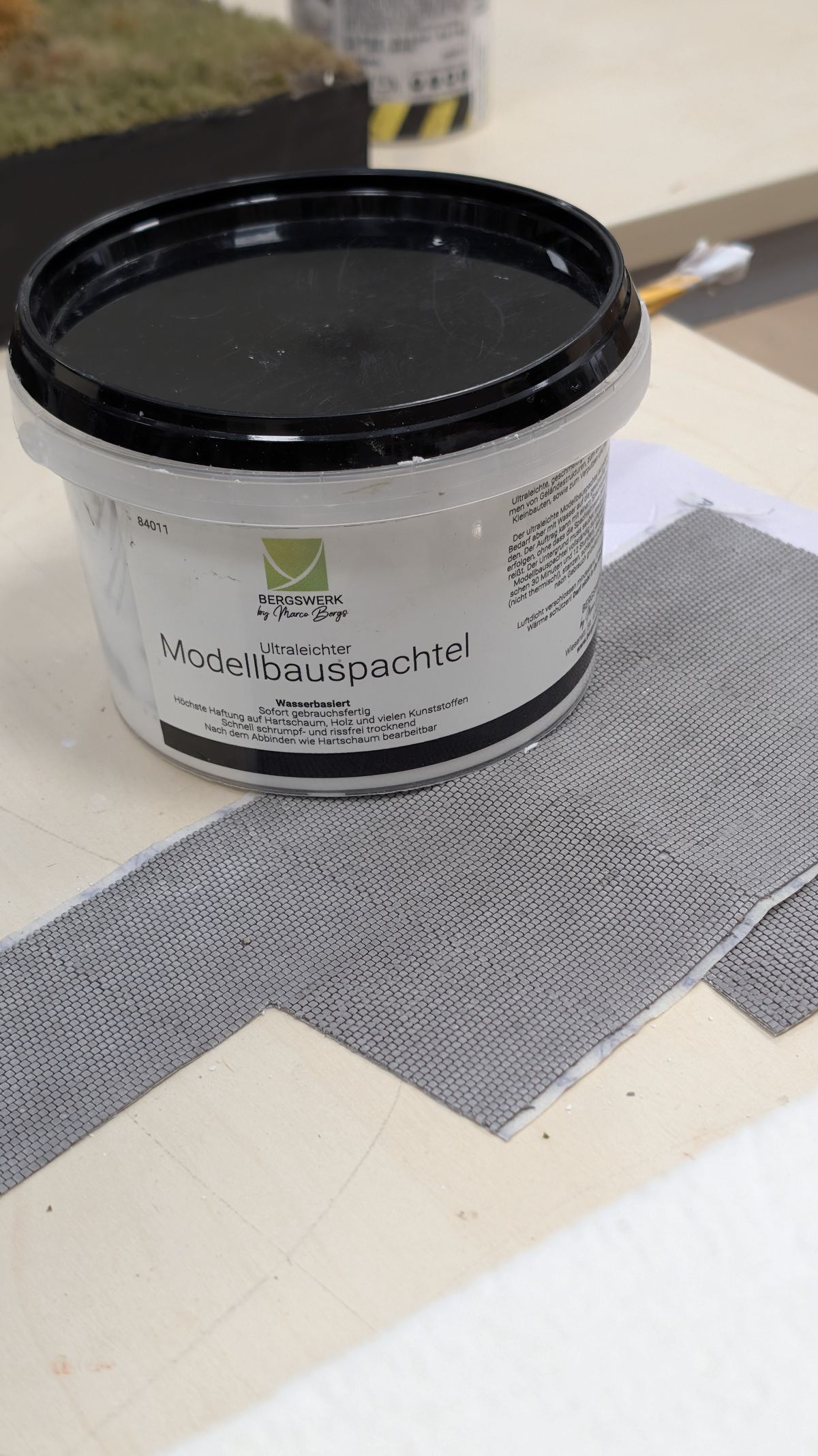 Becher Modellbauspachtel neben Belagsplatten auf der Werkbank