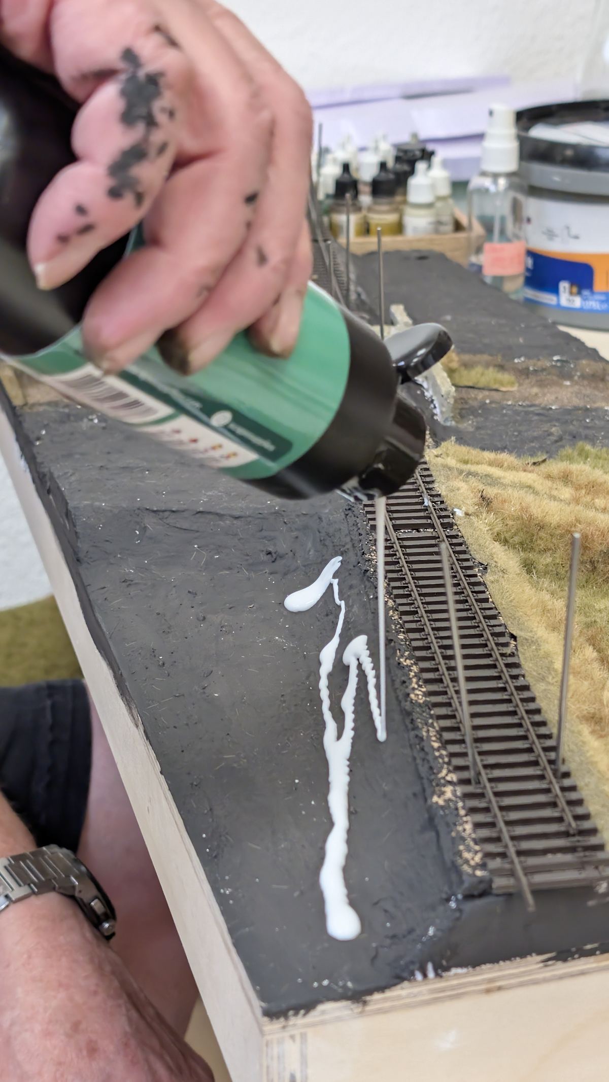 Kleberflasche zieht eine Raupe entlang des verlegten Gleises
